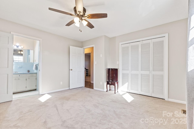 unfurnished bedroom featuring light carpet, ensuite bath, a closet, and ceiling fan