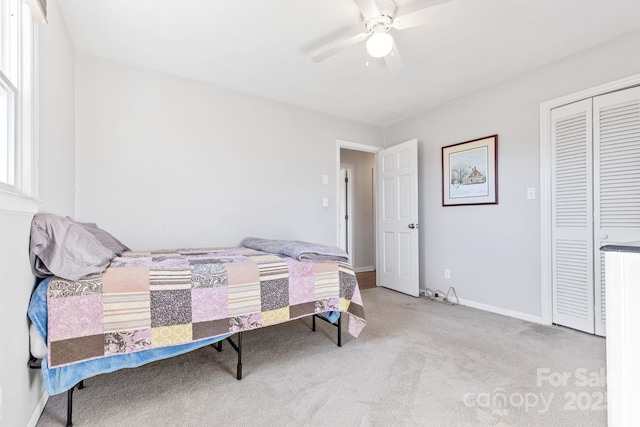 bedroom featuring ceiling fan, light carpet, and a closet