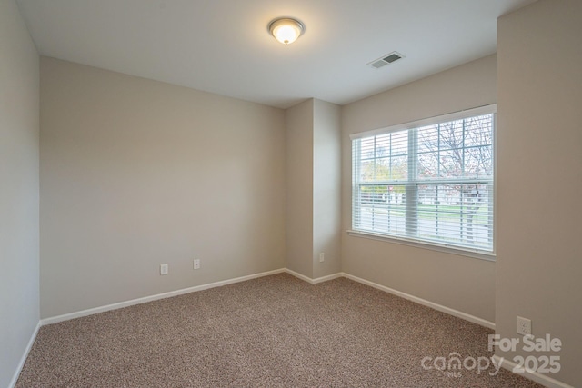 carpeted spare room featuring baseboards and visible vents