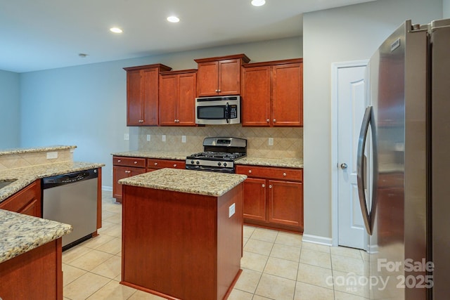 kitchen with light tile patterned floors, appliances with stainless steel finishes, a kitchen island, and decorative backsplash