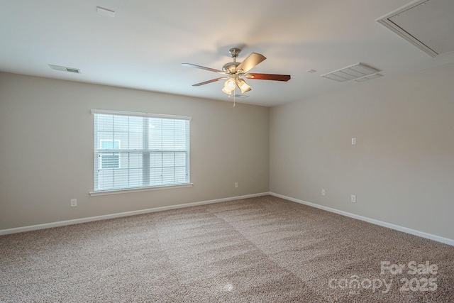 carpeted spare room with attic access, visible vents, ceiling fan, and baseboards