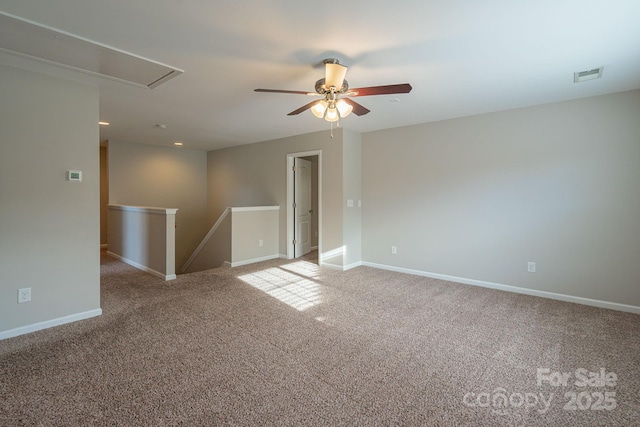 unfurnished room with ceiling fan, visible vents, baseboards, carpet, and attic access