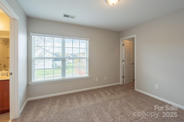 unfurnished room with carpet floors, plenty of natural light, visible vents, and baseboards