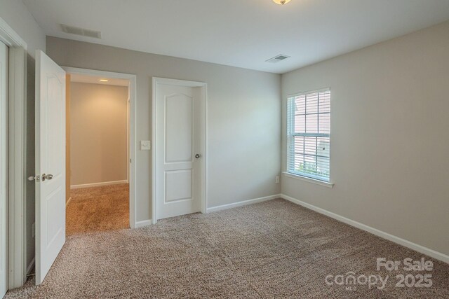 unfurnished bedroom with carpet floors, baseboards, and visible vents