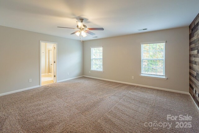 carpeted spare room with baseboards, visible vents, and ceiling fan