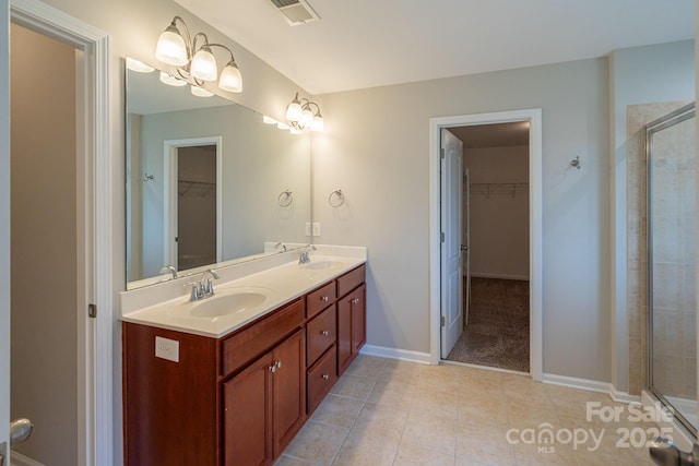 bathroom with a walk in closet, double vanity, visible vents, a sink, and a shower stall