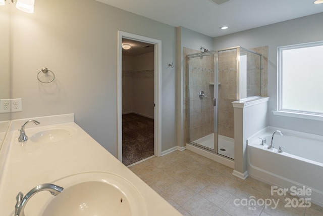 bathroom featuring a sink, a shower stall, a bath, and a spacious closet