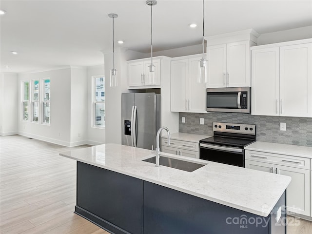 kitchen featuring tasteful backsplash, an island with sink, appliances with stainless steel finishes, white cabinets, and a sink