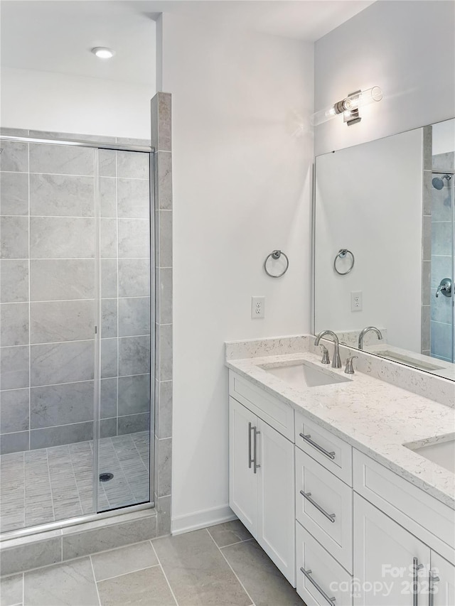 bathroom with double vanity, a sink, a shower stall, and tile patterned floors