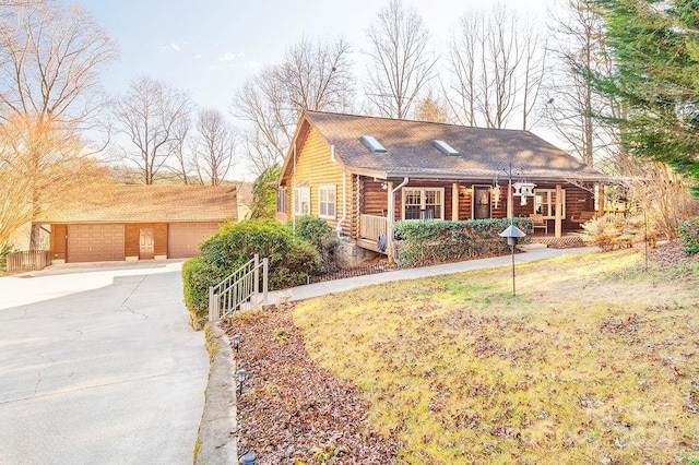 log home with covered porch, a garage, a front lawn, and an outdoor structure