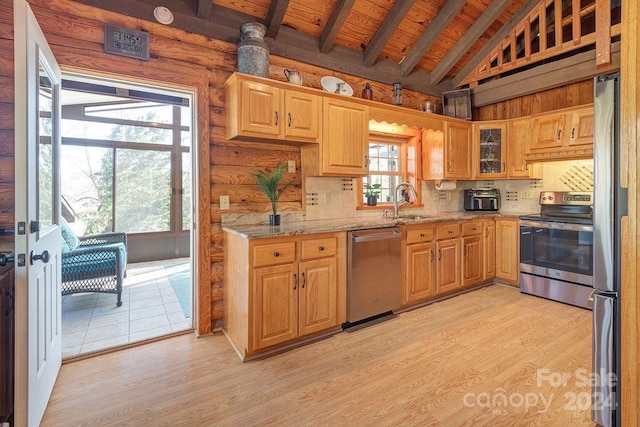 kitchen featuring light stone countertops, lofted ceiling with beams, stainless steel appliances, and light wood-type flooring