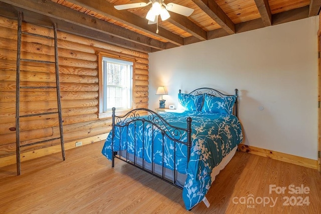 bedroom with ceiling fan, log walls, beam ceiling, hardwood / wood-style flooring, and wooden ceiling