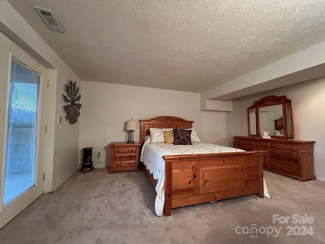 bedroom featuring light carpet and a textured ceiling