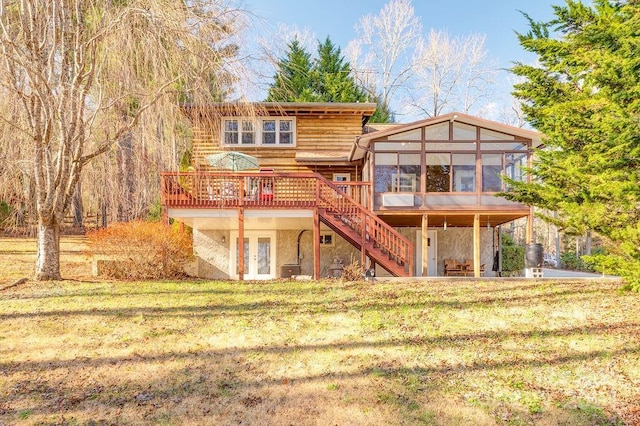 rear view of property with a wooden deck, a lawn, and a sunroom