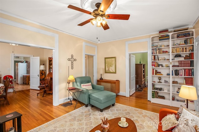 sitting room with hardwood / wood-style floors, ceiling fan, and crown molding