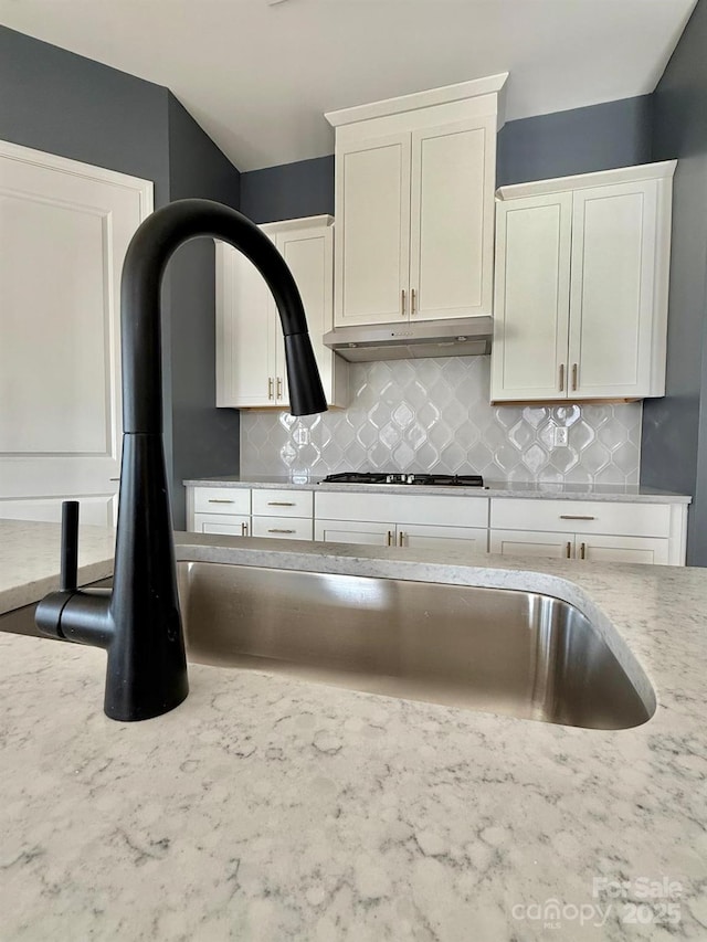 405 Northgate Blvd, Indian Trail, NC 28079 - kitchen with white cabinetry, decorative backsplash, light stone counters, under cabinet range hood, and stainless steel gas stovetop