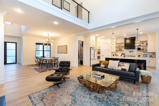 living room with crown molding, light hardwood / wood-style floors, and a notable chandelier