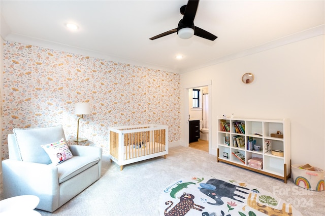 carpeted bedroom featuring ceiling fan, crown molding, and a crib