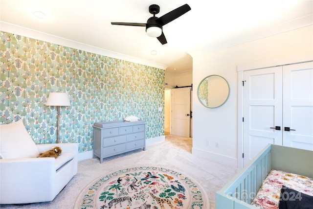 bedroom featuring a barn door, ceiling fan, a closet, and light carpet