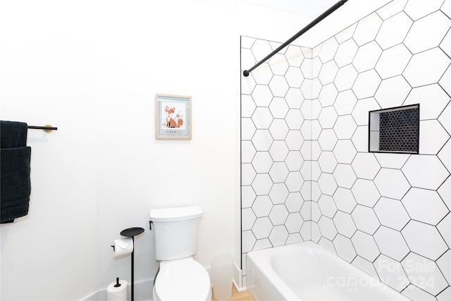 bathroom featuring tiled shower / bath combo and toilet