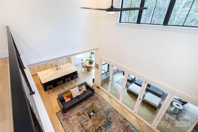 living room with hardwood / wood-style floors, ceiling fan, and a high ceiling