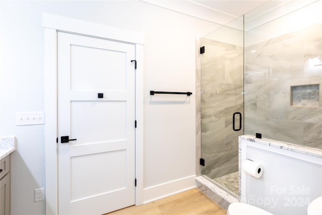 bathroom featuring a shower with door, vanity, wood-type flooring, and toilet