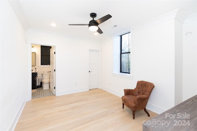 living area with light hardwood / wood-style floors, ceiling fan, and ornamental molding