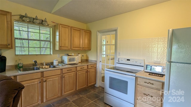 kitchen featuring a textured ceiling, white appliances, sink, and tasteful backsplash