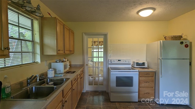 kitchen with backsplash, a textured ceiling, white appliances, dark tile patterned floors, and sink