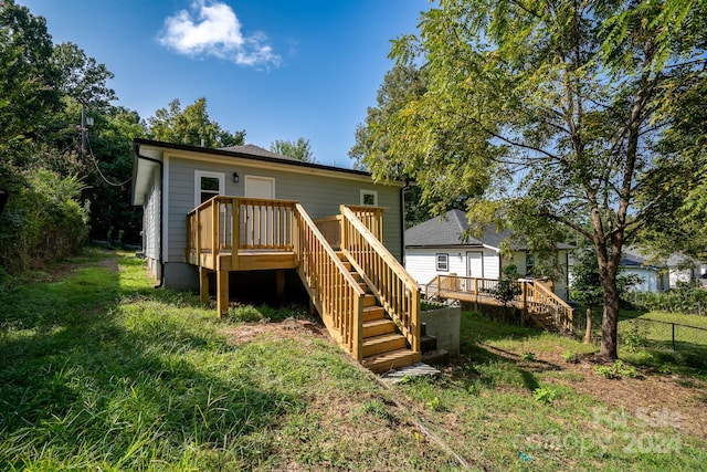 rear view of property featuring a lawn and a wooden deck