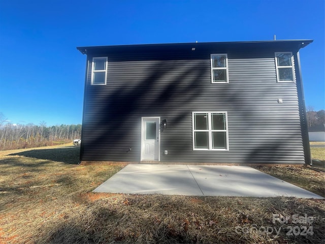 back of property with a yard and a patio