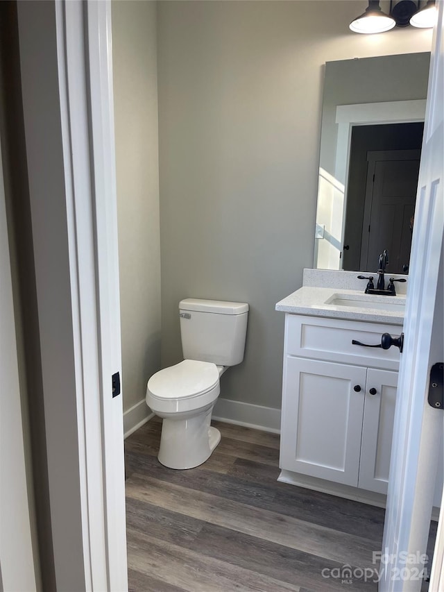 bathroom with toilet, vanity, and hardwood / wood-style flooring