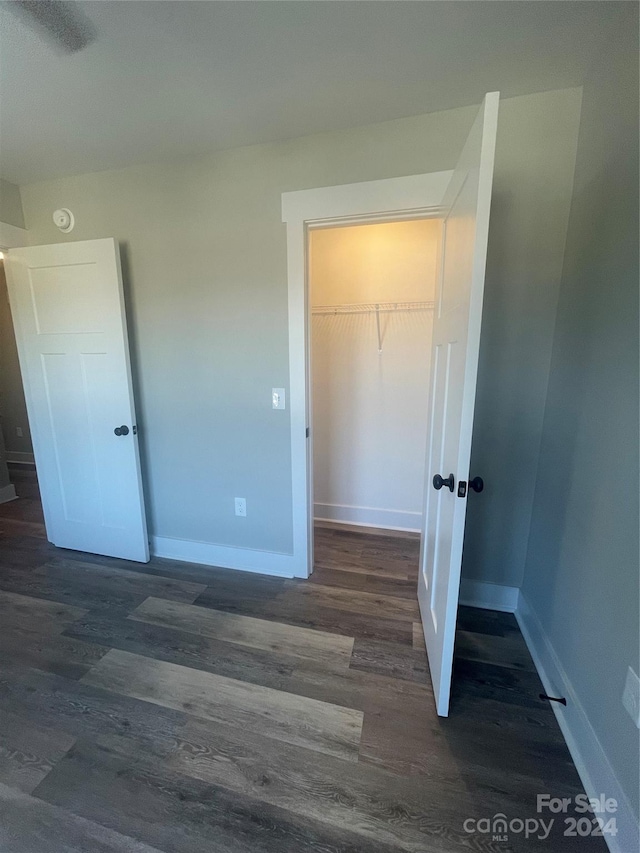 unfurnished bedroom with dark hardwood / wood-style floors, a spacious closet, and a closet