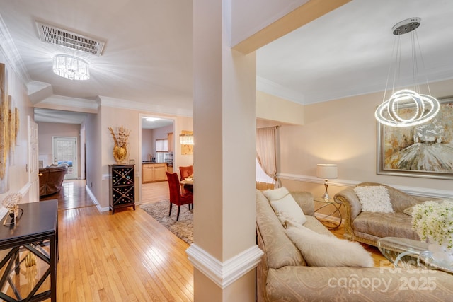 living room with ornamental molding, wood finished floors, visible vents, and baseboards