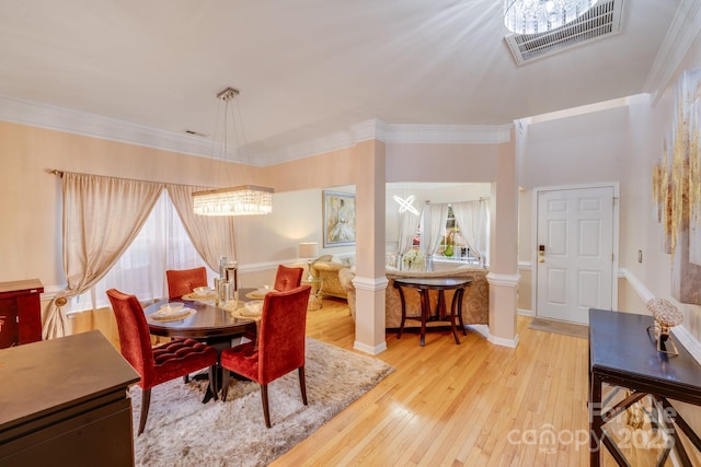 dining space featuring decorative columns, baseboards, visible vents, ornamental molding, and wood finished floors