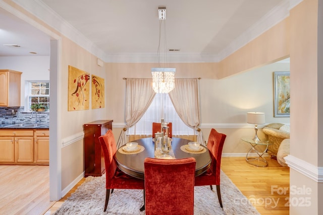 dining space with crown molding, visible vents, a chandelier, light wood-type flooring, and baseboards