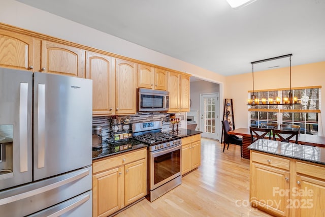 kitchen featuring stainless steel appliances, hanging light fixtures, light brown cabinets, and light wood-style flooring