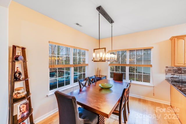 dining room featuring light wood-style floors, baseboards, visible vents, and an inviting chandelier