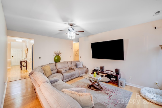 living area with baseboards, a ceiling fan, visible vents, and light wood-style floors