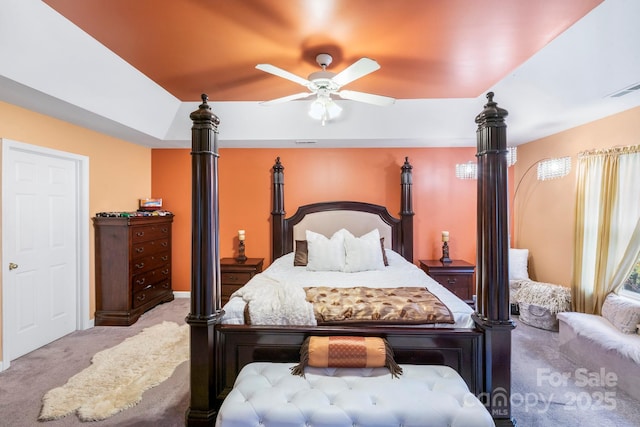 bedroom featuring carpet floors, a tray ceiling, visible vents, and a ceiling fan