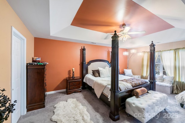 bedroom featuring a raised ceiling, light colored carpet, visible vents, a ceiling fan, and baseboards