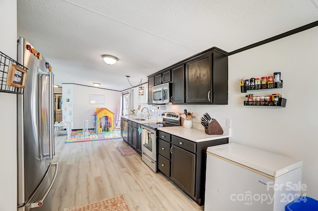 kitchen with a textured ceiling, stainless steel appliances, crown molding, and light hardwood / wood-style floors