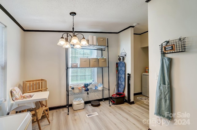 dining room featuring washer / dryer, a textured ceiling, an inviting chandelier, and light hardwood / wood-style flooring