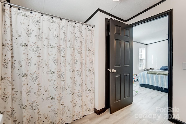 bathroom with hardwood / wood-style floors, a textured ceiling, walk in shower, and crown molding