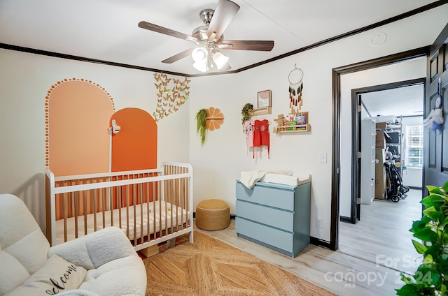 bedroom with ceiling fan, light hardwood / wood-style flooring, crown molding, and a nursery area