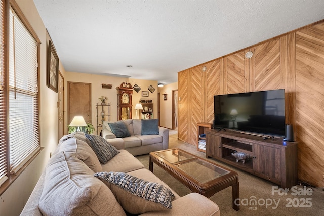 carpeted living room featuring a textured ceiling and wooden walls