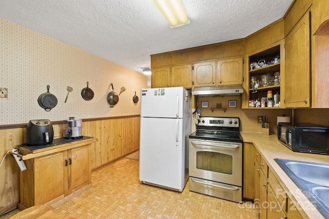 kitchen with sink, white refrigerator, wood walls, a textured ceiling, and electric stove