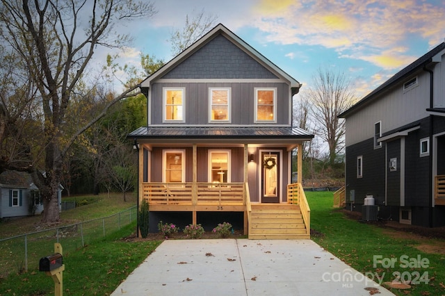 view of front of home with a lawn, a porch, and central AC unit