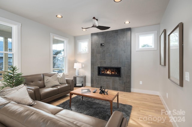 living room featuring a tiled fireplace, ceiling fan, and hardwood / wood-style floors