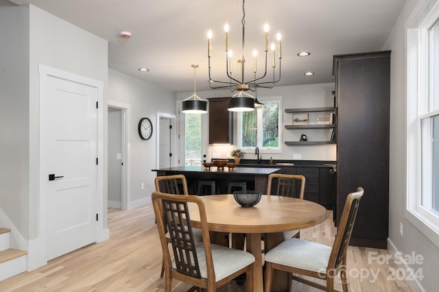 dining room with an inviting chandelier, sink, and light hardwood / wood-style flooring